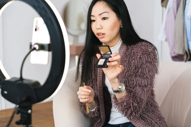 Young woman recording a makeup tutorial with a ring light for her vlog. Checking influencer audience quality