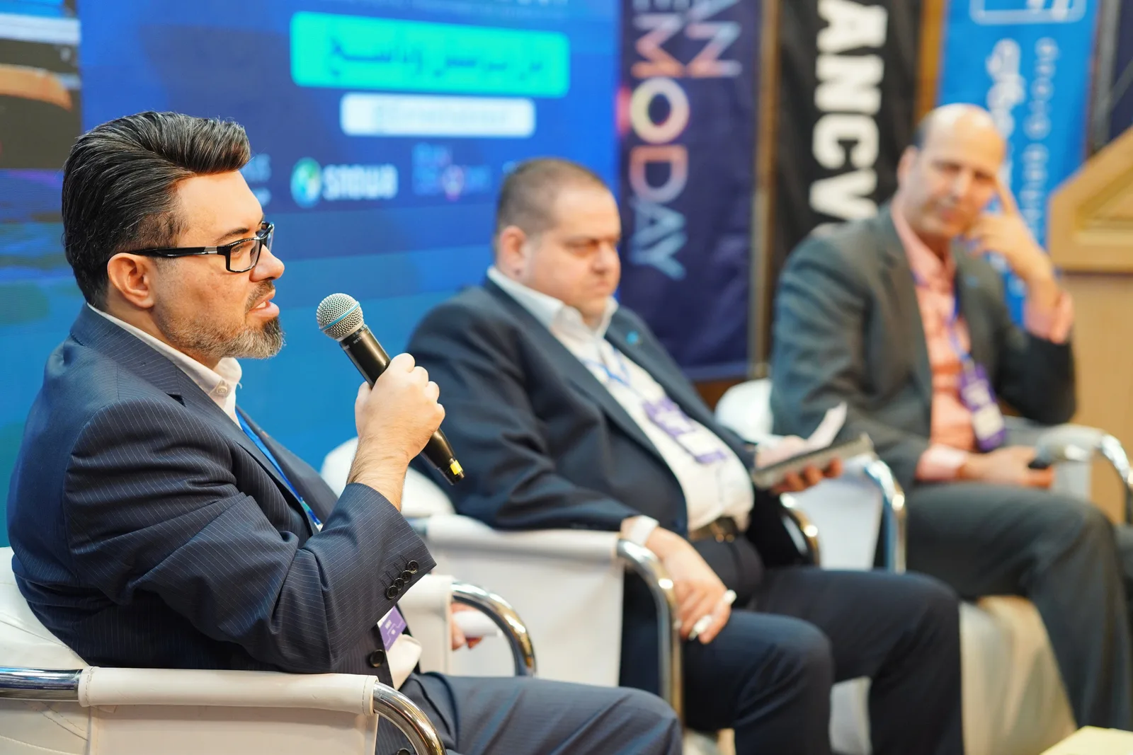 Three men engaged in a panel discussion at a professional conference.